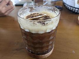 Arabica Kaffee Eis mit getrocknet Zitrone Scheibe mit Sahne schäumen. das Foto ist geeignet zu verwenden zum Kaffee Geschäft Hintergrund, Speisekarte Poster und Kaffee Inhalt Medien.