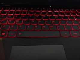 Tastatur mit rot Hintergrundbeleuchtung SMS durch Hand. das Foto ist geeignet zu verwenden zum Laptop Hintergrund Aktivität und Bedienung Inhalt Medien.