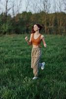 ein sportlich Frau läuft und Züge ihr Körper Vor das Sommer- Jahreszeit im das Park foto