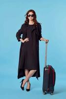 Frau im schwarz Mantel Gepäck Flughafen Reise Blau Hintergrund Geschäft Ausflug foto