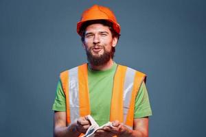 Mann im Konstruktion Uniform Orange Helm Sicherheit Emotionen Blau Hintergrund foto