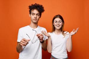 heiter jung Paar im Weiß T-Shirts Emotionen Kommunikation Orange Hintergrund foto