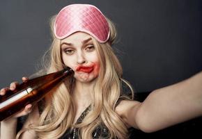 betrunken Frau mit ein Flasche von Bier haben Spaß auf ein grau Hintergrund und gestikulieren mit ihr Hände foto