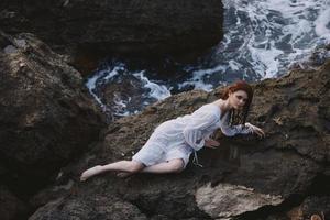 barfuß Frau Lügen auf ihr zurück auf ein felsig Strand unverändert foto