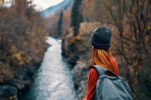 Frau mit Rucksack im Natur auf das Brücke in der Nähe von das Fluss Berge Abenteuer foto