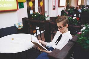 Schüler mit ein Buch im seine Hände draußen im ein Sommer- Cafe sich ausruhen Kommunikation foto