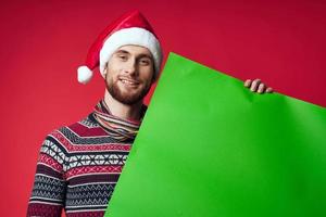 emotional Mann im ein Santa Hut halten ein Banner Urlaub rot Hintergrund foto