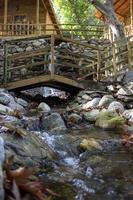 hölzern Brücke Über ein klein Strom im das Wald. Wasserfall im das Garten mit Felsen und Blätter im das Herbst Jahreszeit. hölzern Brücke Über ein Strom im das Garten von ein Land Haus foto