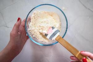 Frau, die Mehl in einer Glasschüssel auf weißem Hintergrund mischt foto