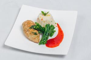 schwenken geröstet Hähnchen Brust mit lange Grün Bohnen und Licht Gemüse Reis Teller. Essen dekorieren mit rot Soße auf ein Weiß Platte. isoliert Weiß Hintergrund. foto