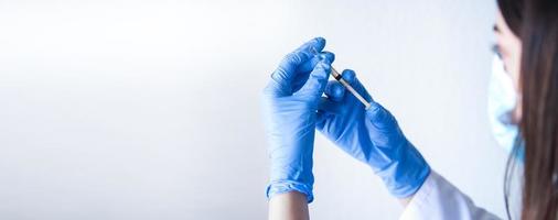 Krankenschwester im Profil, das Impfstoff mit blauen Handschuhen auf weißem Hintergrund mit Platz für Text hält