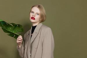 ziemlich Frau im Mantel rot Lippen Mode Palme Blatt Studio Modell- unverändert foto