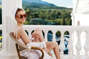 sinnlich und schön Frau im Sonnenbrille sitzt auf ein öffnen Balkon Entspannung Konzept foto