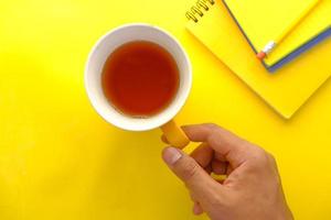 Hand, die eine Tasse grünen Tee auf gelbem Hintergrund hält