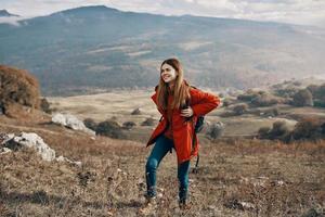 Frau mit Rucksack Reise Berge Landschaft Jacke Stiefel Jeans foto