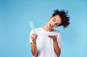 heiter Kerl mit lockig Haar und Blau Haarbürste isoliert Hintergrund Modell- abgeschnitten Aussicht foto