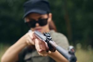 Frau auf Natur halten ein Gewehr Sicht Jagd Grün Blätter Grün Bäume foto