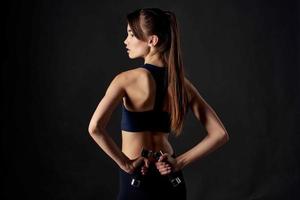 Sport Frau mit Hanteln im Hände trainieren Fitness dunkel Hintergrund foto