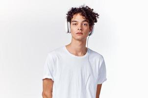 Teenager T-Shirt und im Kopfhörer auf ein Licht Hintergrund Neu Technologie Modell- foto