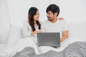 jung glücklich asiatisch Paar mit Laptop im Bett Aufpassen Film, romantisch Zeit zu verbessern Familie Beziehung, Familie Konzept. foto