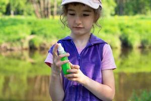 mädchen sprüht mückenspray auf die haut in der natur, die ihre hände und füße beißen. Schutz vor Insektenstichen, Repellent sicher für Kinder. Erholung im Freien, gegen Allergien. Sommerzeit foto