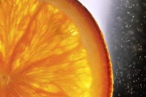Orange Scheibe Makro mit ein fallen von Wasser Hintergrund . saftig Orange geschnitten Nahansicht auf ein dunkel Hintergrund foto