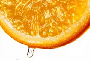 Orange Scheibe mit ein fallen von Wasser schließen oben auf ein Weiß Hintergrund foto