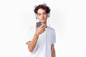 lockiges Haar Kerl im Kopfhörer mit ein Telefon im seine Hände Musik- Technologie foto