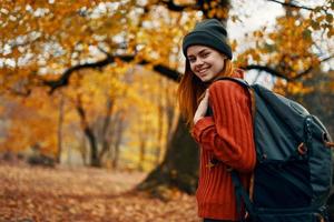 glücklich Frau mit Rucksack Gehen im Park im Natur im Herbst abgeschnitten Aussicht foto