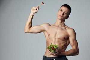 sportlich Kerl mit ein muskulös Torso hält ein Teller von Salat im seine Hand Mahlzeit Energie trainieren foto