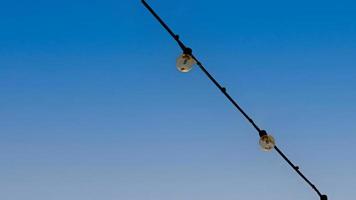 Gruppe von Licht Glühbirnen hängend auf Drähte gegen auf Blau Himmel. foto