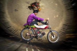 Bangladesch Februar 14, 2018 ein ländlich Kunststück Biker ist riskieren seine Leben durch Skalierung das Mauer von ein groß hölzern Gut im ein Motorrad Karneval Nebenschau beim Dohar, dhaka. foto