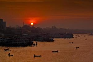 das Morgen von das rot Sonnenaufgang Über das geräuschfrei Buriganga Fluss beim Sadarghat, dhaka. foto
