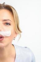 komisch Kosmetikerin mit ein Weiß federartig Schnurrbart posiert auf Weiß Hintergrund, Enthaarung Konzept. foto