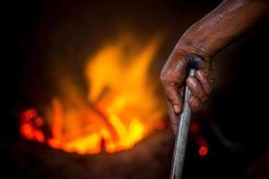 unsicher Arbeiter Hände. ein lokal Stahl Maschine Teile Herstellung Hof Arbeiter schmelzen Schrott auf heiß Ofen. foto
