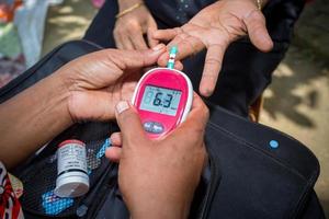 Frau Überprüfung Zucker Niveau mit Glukometer mit ein Blut Stichprobe beim Narsingdi, Bangladesch. lernen zu verwenden ein Blutzuckermessgerät. Konzept von Diabetes Behandlung. foto