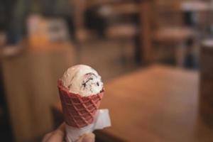 lecker kalt cremig Vanille Eis Sahne im ein rot Zucker Kegel gehaltenen im Ihre Hand foto