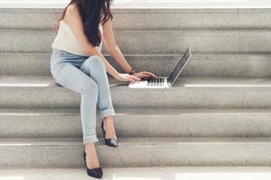 berufstätige Frau benutzt einen Computer, der auf Treppen sitzt foto