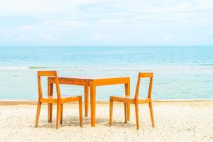 Holztisch und Stuhl zum Abendessen am Strand foto
