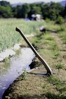 Hacke beim das Kante von das Garten entlang ein klein Strom während das Tag foto