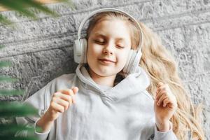 wenig Mädchen Hören Musik- Lügen auf das Fußboden foto