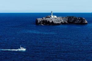 Aussicht von das Magdalena Halbinsel, Weihnachtsmann, Spanien, mit ein klein Boot Segeln und das Muro Insel im das Hintergrund mit es ist 19 .. Jahrhundert Leuchtturm foto