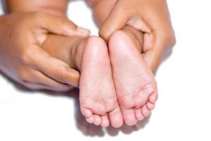 ein Mama halten Babys zwei Füße auf ein Weiß Hintergrund. foto