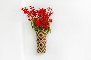 Bambus Blume Vase mit rot lila Blumen hängend auf das Weiß Mauer. isoliert Hintergrund. foto