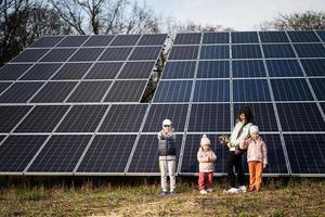 Mutter mit drei Kinder auf das Hintergrund von Solar- Tafeln. Öko Energie. foto