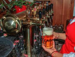 Slowakei, Bratislava - - 01.07.2023 weiblich Barmann Hände Gießen dunkel Bier von das Zapfhahn im Bar. foto