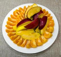geschält Mandarinen geschnitten und rot und Gelb Äpfel Schnitt in Scheiben auf ein Weiß Platte. gesund Essen Konzept. foto