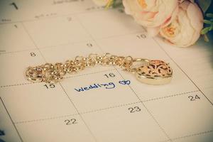 Wort Hochzeit auf Kalender und Gold Armband mit Herz foto