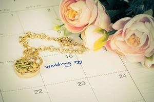 Wort Hochzeit auf Kalender und Gold Armband mit Herz foto