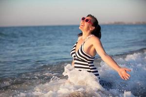 ein schön alt Frau beim Meer. ein schön mittleren Alters Frau spritzt Meer Wasser. foto